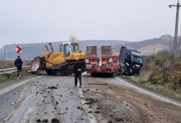 Un buldoexcavator a căzut de pe un trailer peste o maşină. O tânără a decedat