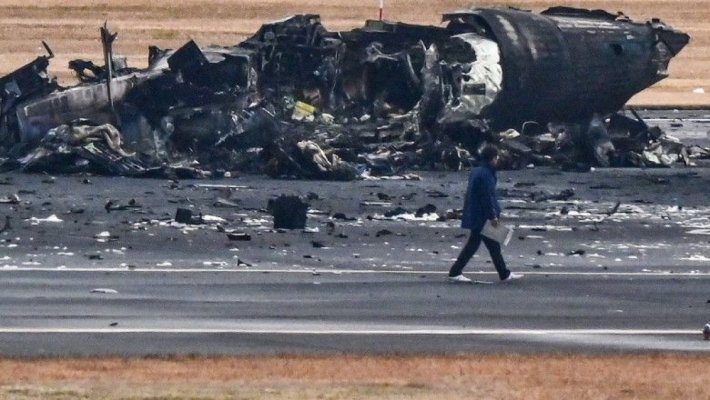 Imagini de pe aeroportul din Tokyo, cu epava înnegrită a avionului distrus de flăcări