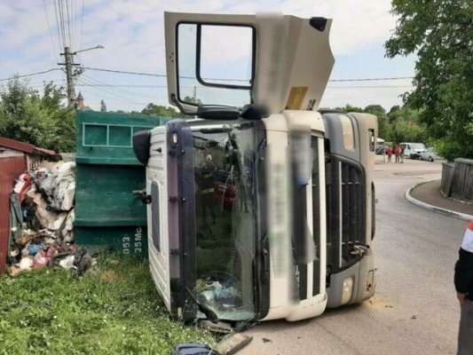 Un camion care transporta gunoi menajer s-a răsturnat lângă gardul unei case